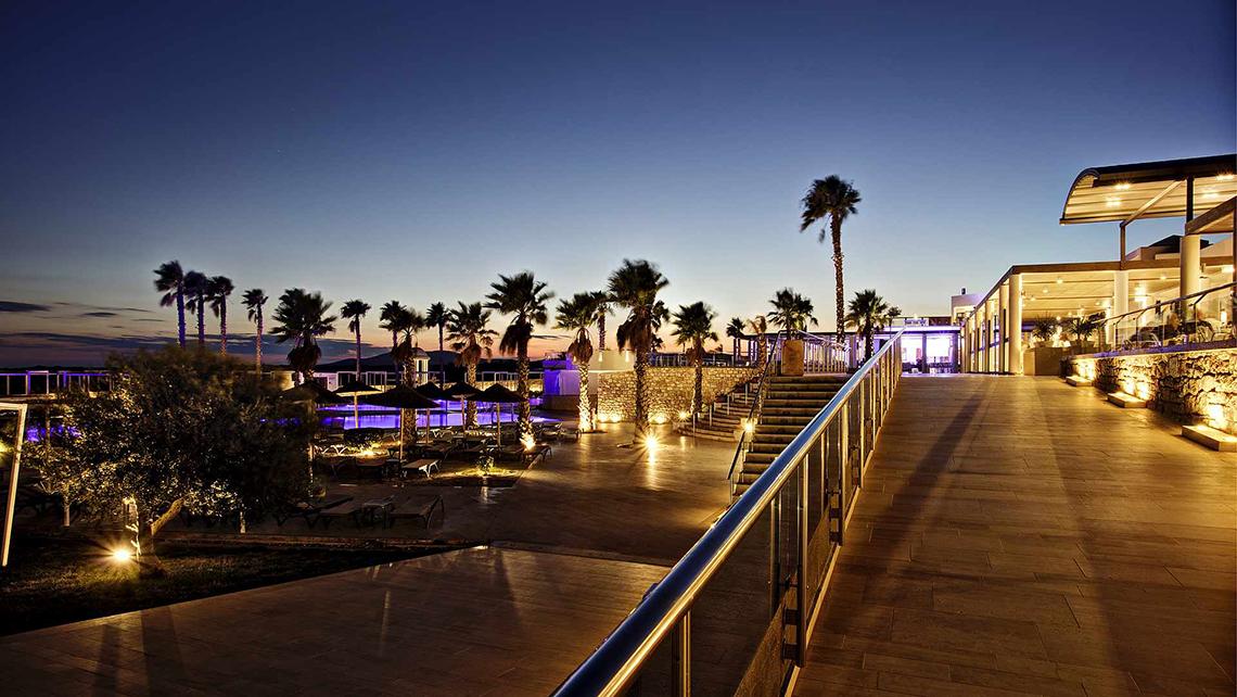 Abendansicht des Club Plimmiri Hotels mit beleuchteten Palmen und Pool.