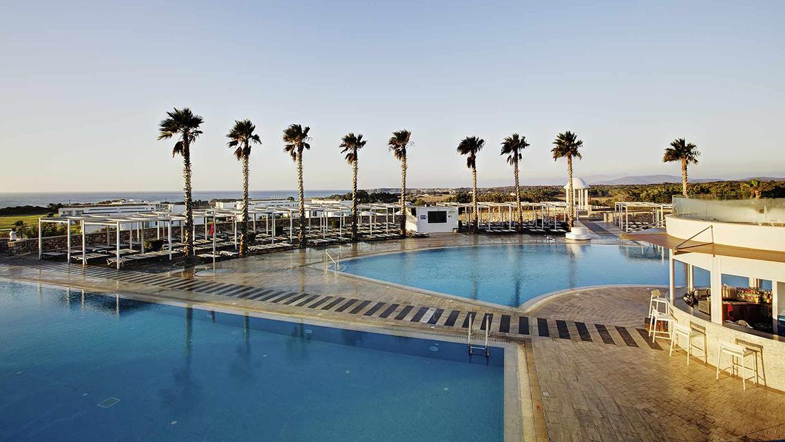 Außenbereich des Club Plimmiri Hotels mit Swimmingpool und Liegestühlen.