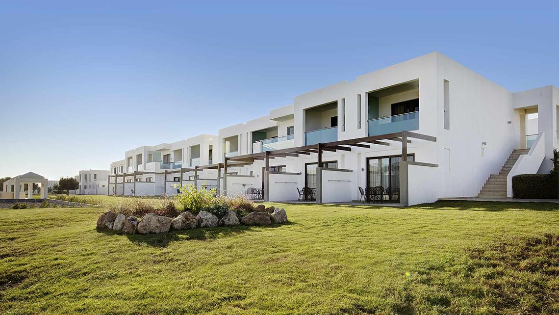 Außenansicht des Club Plimmiri Hotels mit weißen Gebäuden und grünem Rasen
