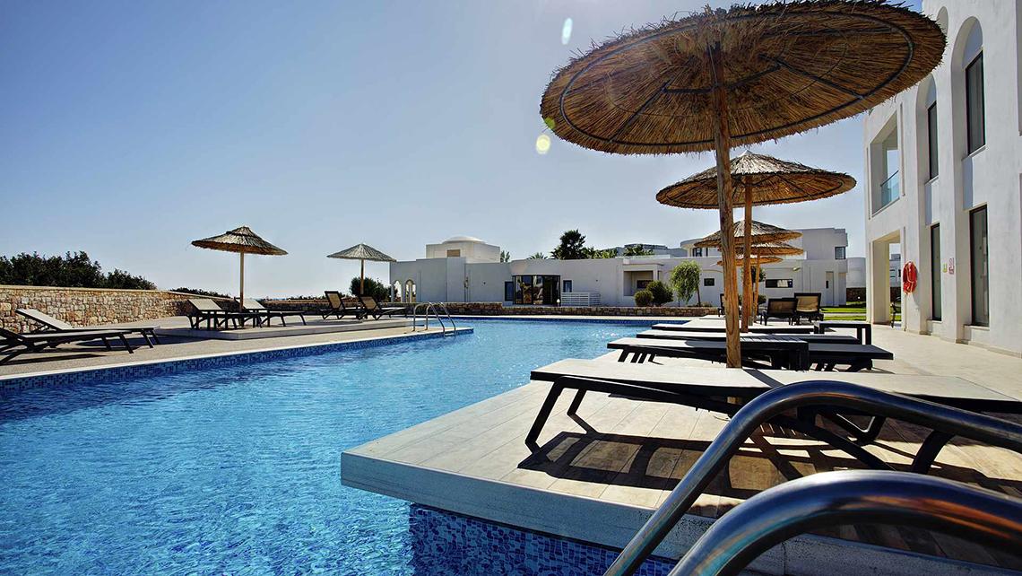 Außenpoolbereich des Club Plimmiri Hotels mit Sonnenliegen und Sonnenschirmen
