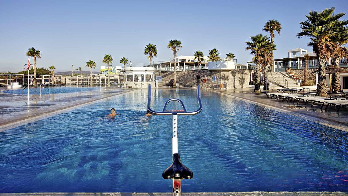 Zwei Personen schwimmen im großen Schwimmbecken des Club Plimmiri Hotels.