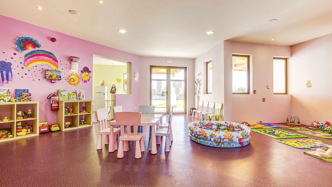 Kinderzimmer im Club Plimmiri Hotel mit bunten Wänden, Spielzeug und Spielbereich.