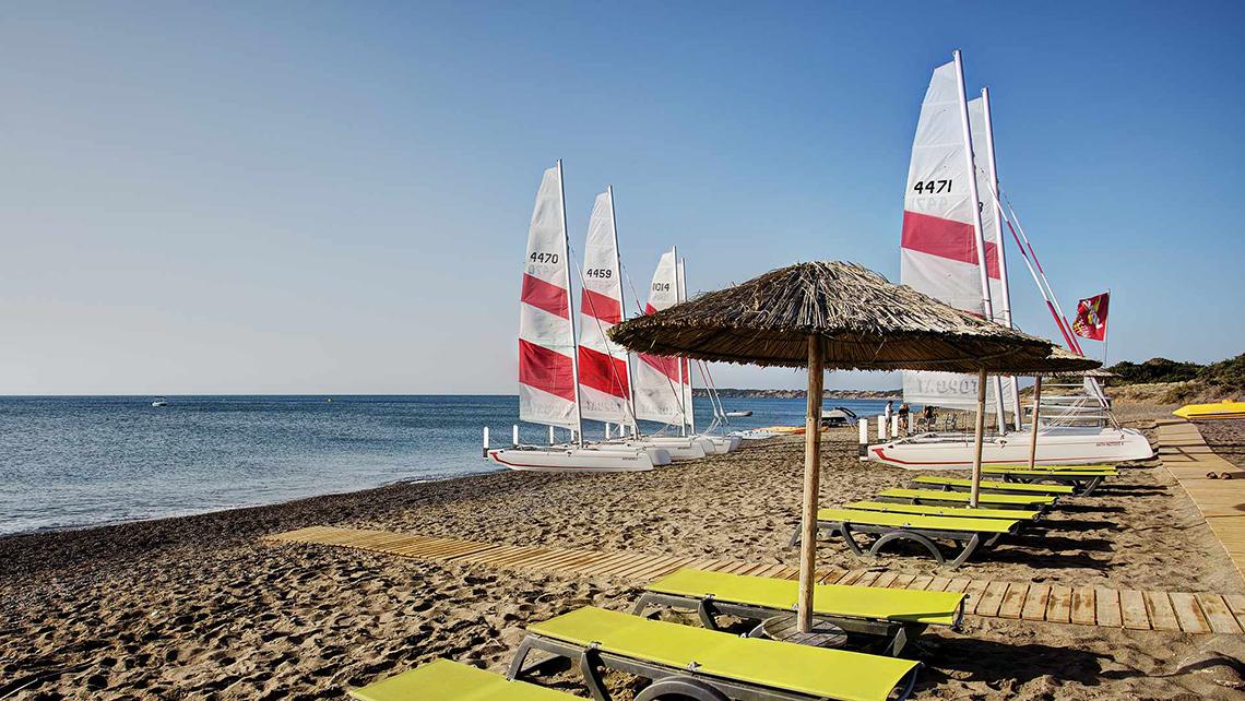 Segelboote und Sonnenliegen am Strand des Club Plimmiri Hotels.