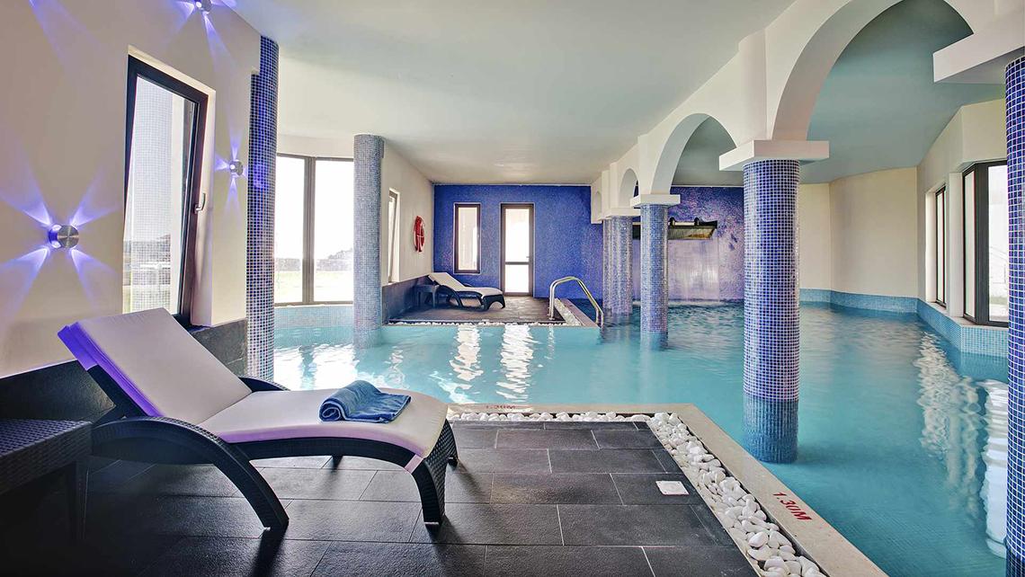 Pool-Loungebereich im Club Plimmiri Hotel mit blauen Säulen und Liegestühlen.