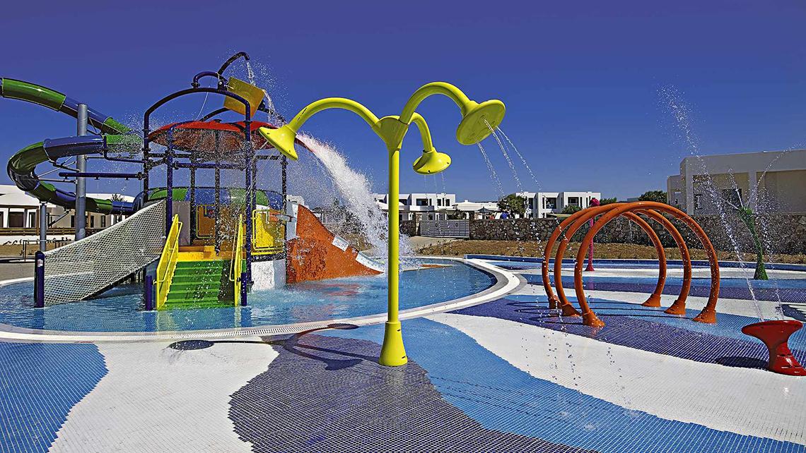 Wasserspielplatz im Club Plimmiri Hotel mit bunten Rutschen und Wasserfontaenen.