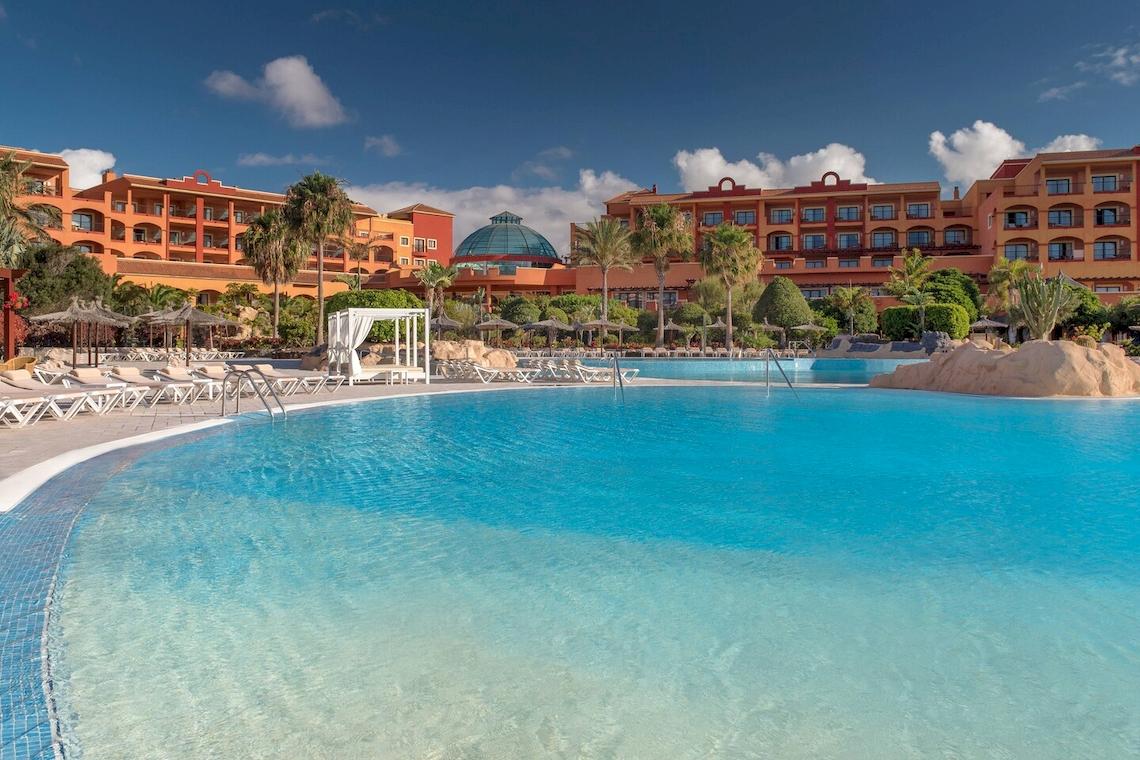 Poolbereich des Sheraton Fuerteventura Beach, Golf & Spa Resorts mit Loungeliegen und Hotelgebäude im Hintergrund.