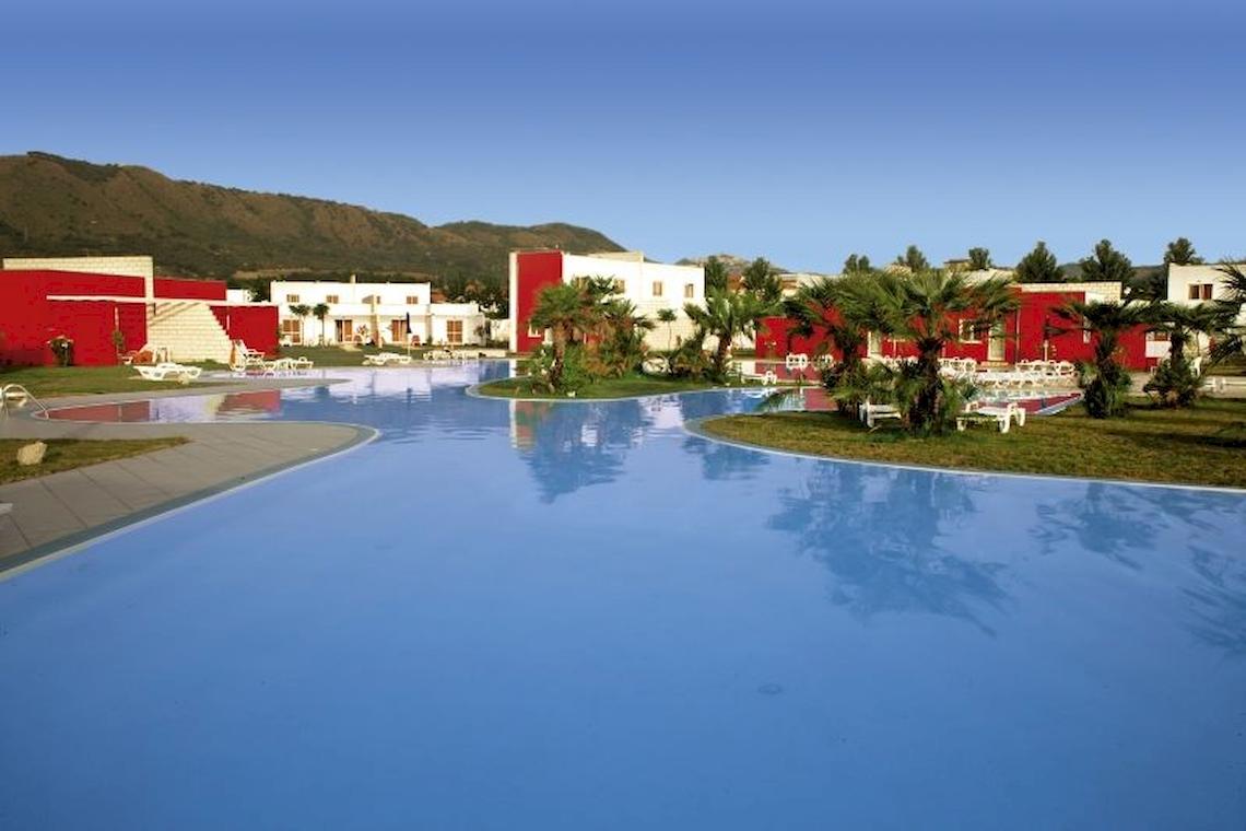 Außenpool des Club Esse Sunbeach Village Hotels mit roten Gebäuden und Palmen