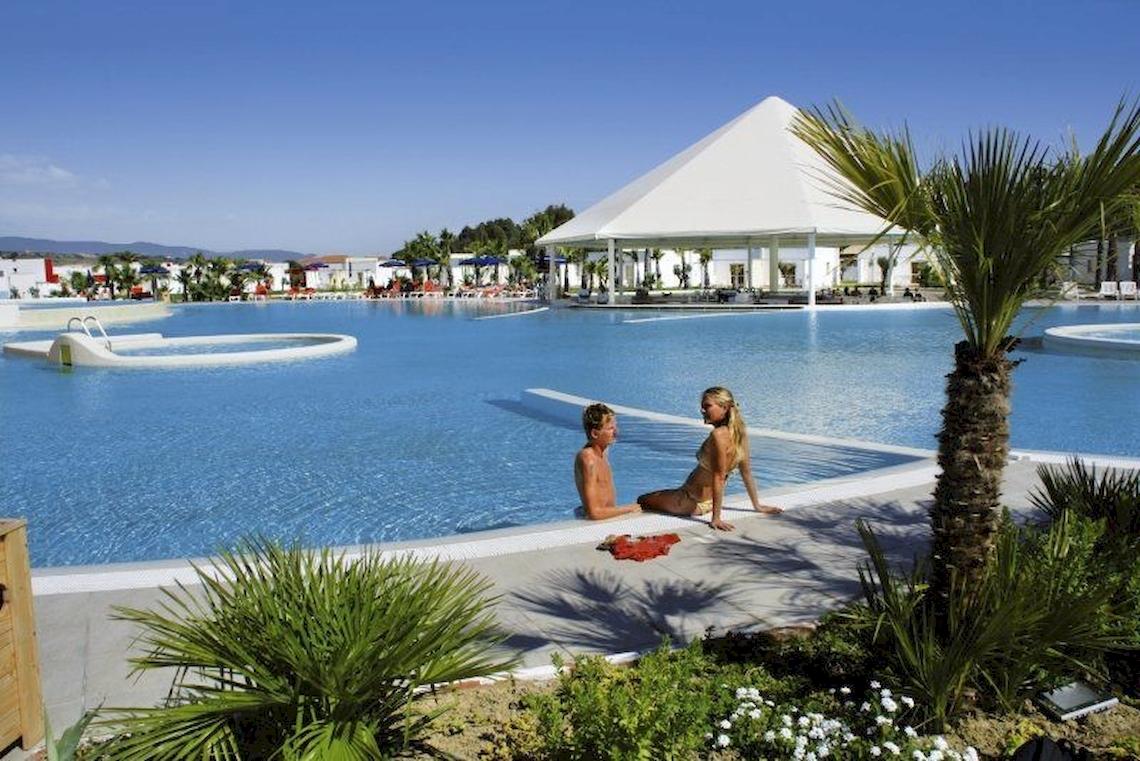 Außenpool im Club Esse Sunbeach Village mit zwei Personen und Pflanzen.