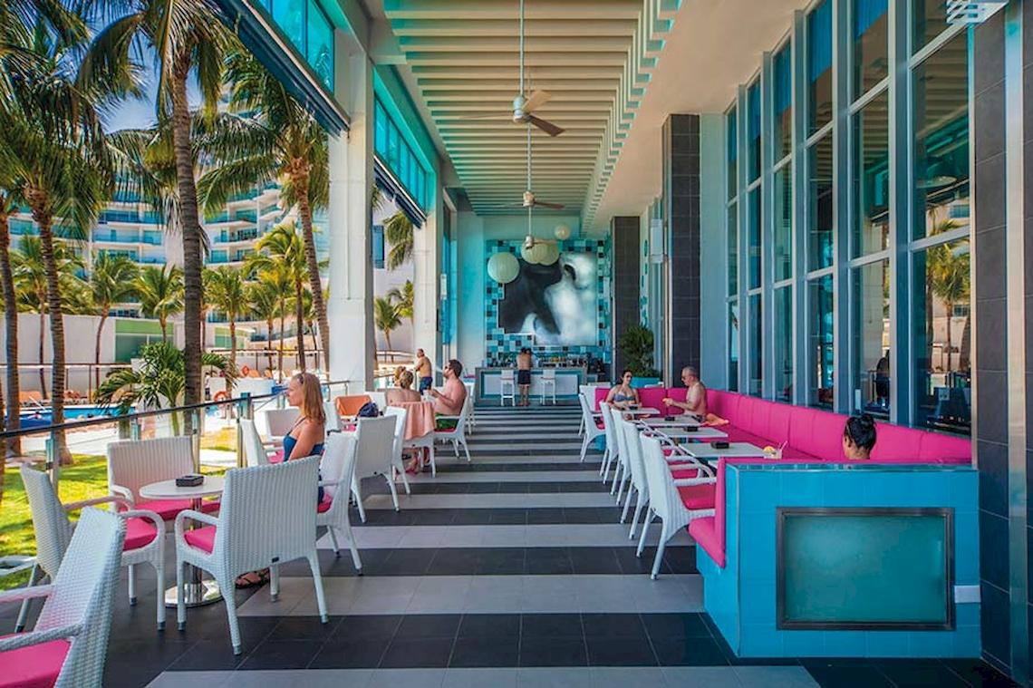 Loungebereich des Riu Cancun Hotels mit bunten Sitzgelegenheiten und Palmen.
