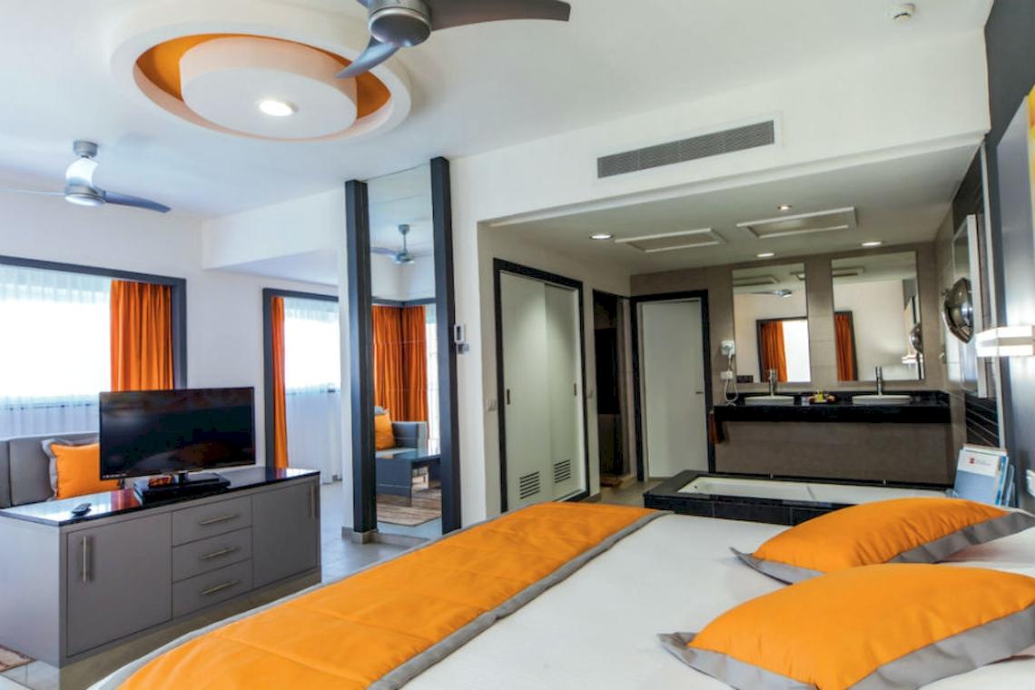 Innenansicht eines Hotelzimmers im Riu Cancun mit Fernseher, Bett und Badezimmer.