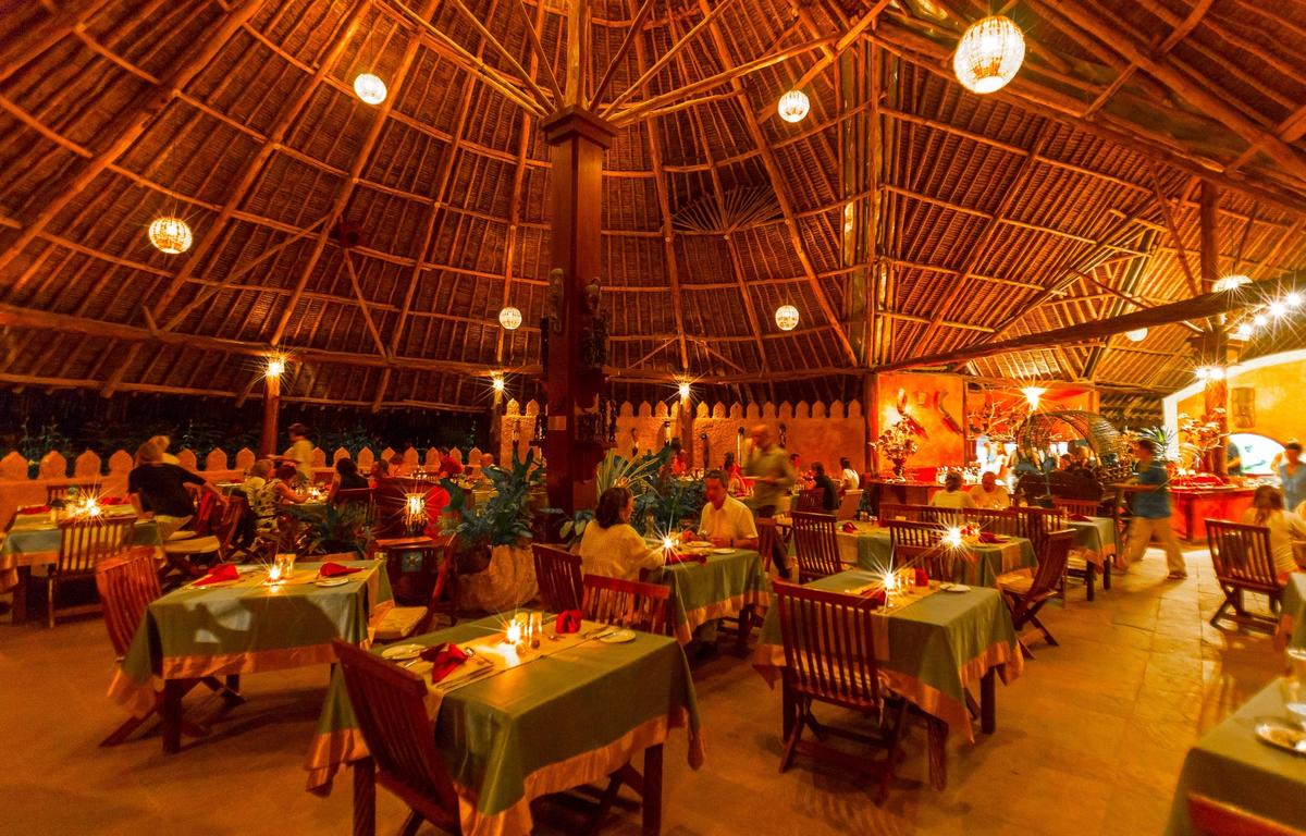 Innenbereich des Restaurants im Sands at Chale Island Resort mit beleuchteten Tischen und Stühlen.