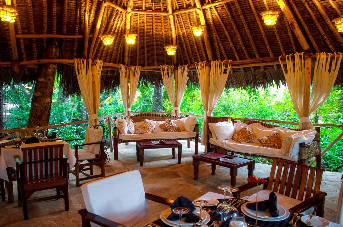 Innenbereich des Sands at Chale Island Resort mit gepolsterten Sofas, Tischen und Stühlen.