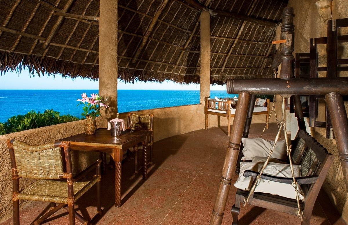 Balkon mit Meerblick im Sands at Chale Island Resort, mit Tisch, Stühlen und Hängesessel.