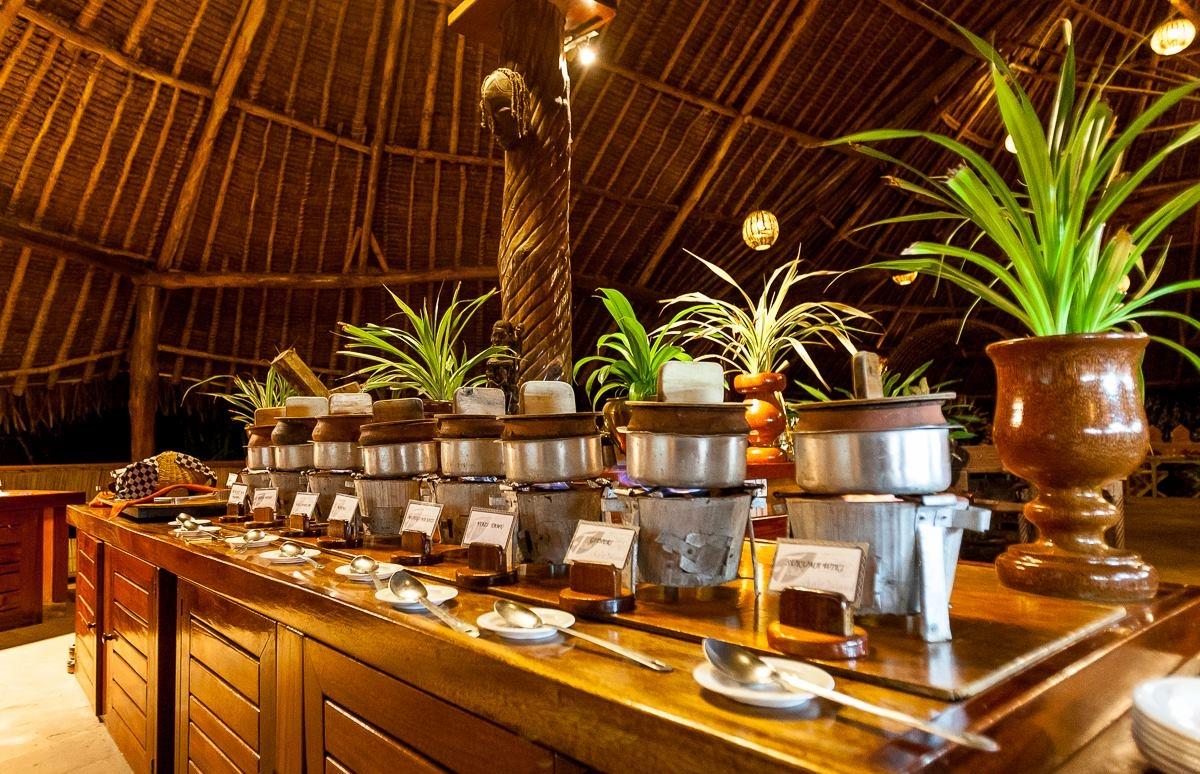 Speisebereich im Sands at Chale Island Resort mit Pflanzen und Töpfen.