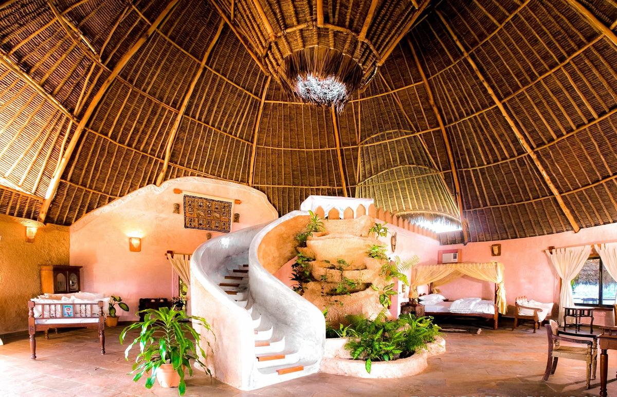 Innenansicht des Sands at Chale Island Resorts mit geschwungener Treppe und Pflanzen.