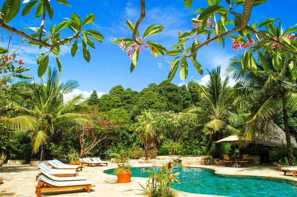 Außenpoolbereich des Sands at Chale Island Resort mit Sonnenliegen und Sonnenschirm.