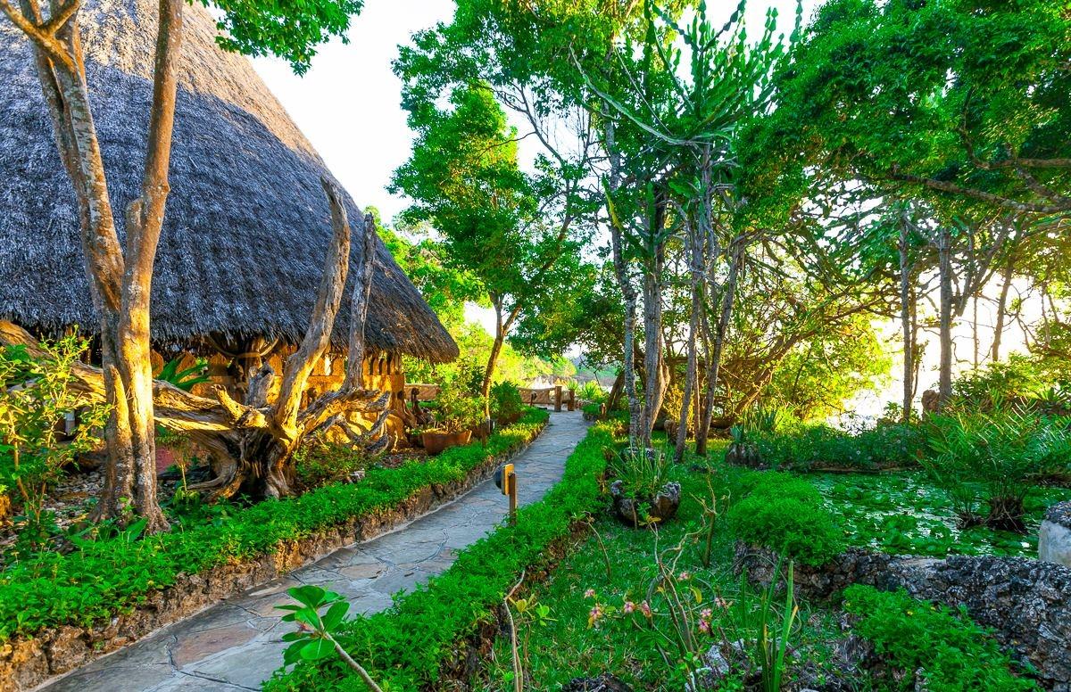 Weg zum Bungalow im Sands at Chale Island Resort mit bewachsenem Pfad und umliegenden Pflanzen.
