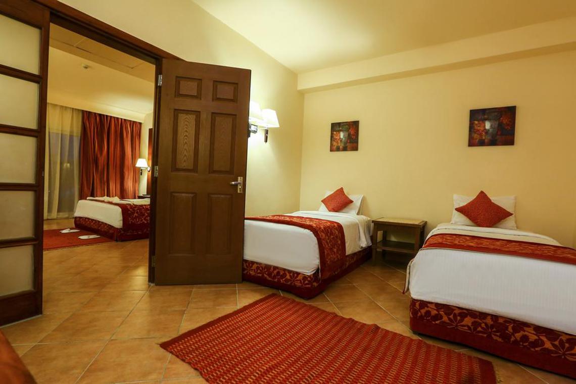 Hotelschlafzimmer des Charmillion Club Aqua Park mit zwei Betten, Tisch und Bildern an der Wand.