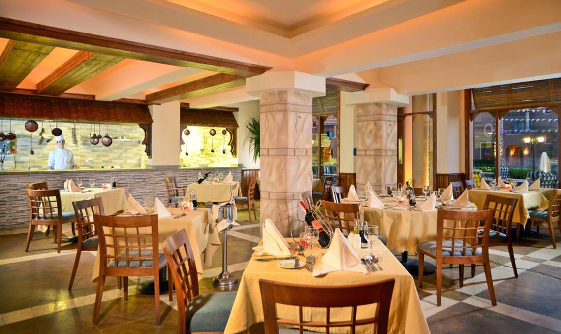 Innenansicht des Restaurants im Charmillion Club Aqua Park mit gedeckten Tischen und einem Koch hinter der Theke.