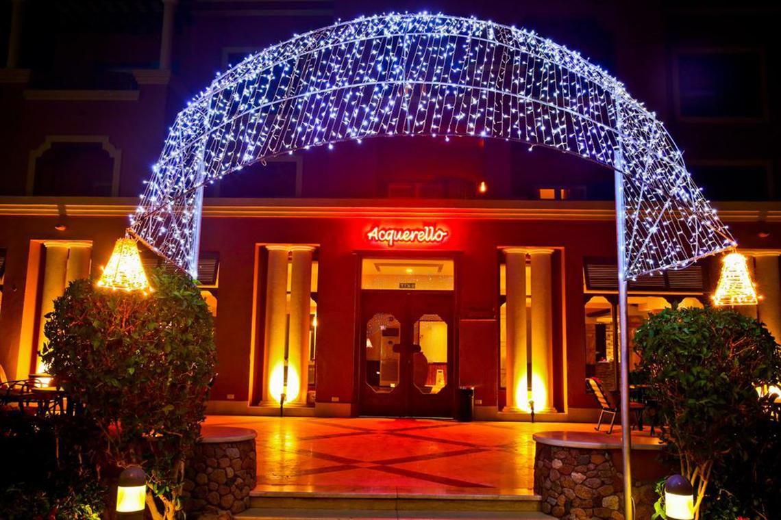 Der beleuchtete Eingang des Charmillion Club Aqua Park Hotels mit einem bogenförmigen Lichtervorhang.