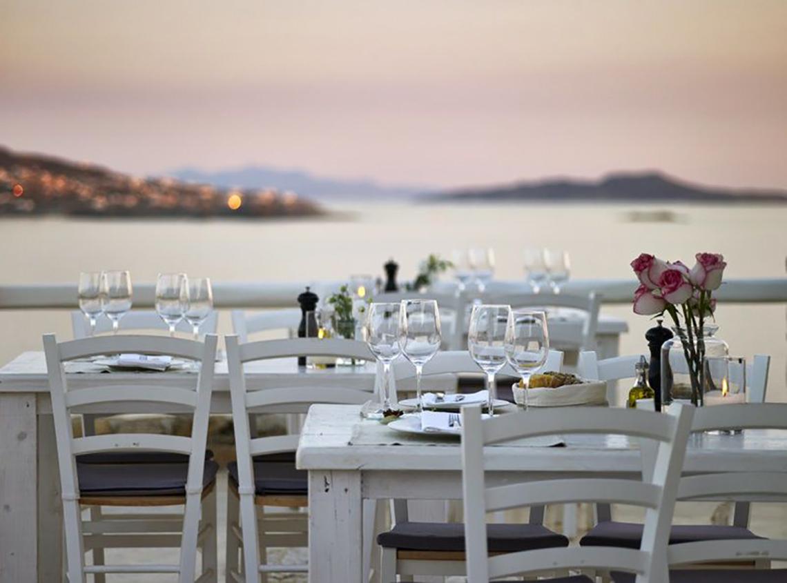 Terrasse des Rocabella Mykonos Art Hotel & Spa mit Blick auf das Meer bei Sonnenuntergang.