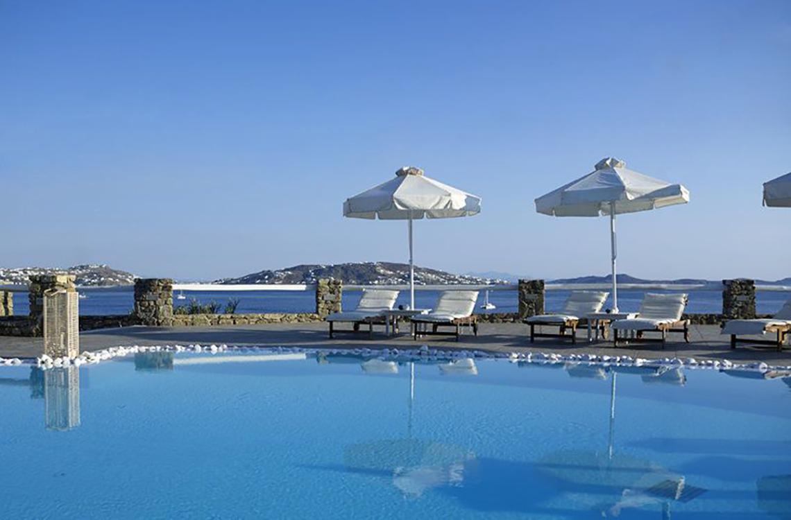 Außenpool des Rocabella Mykonos Art Hotel mit Sonnenliegen und Sonnenschirmen.
