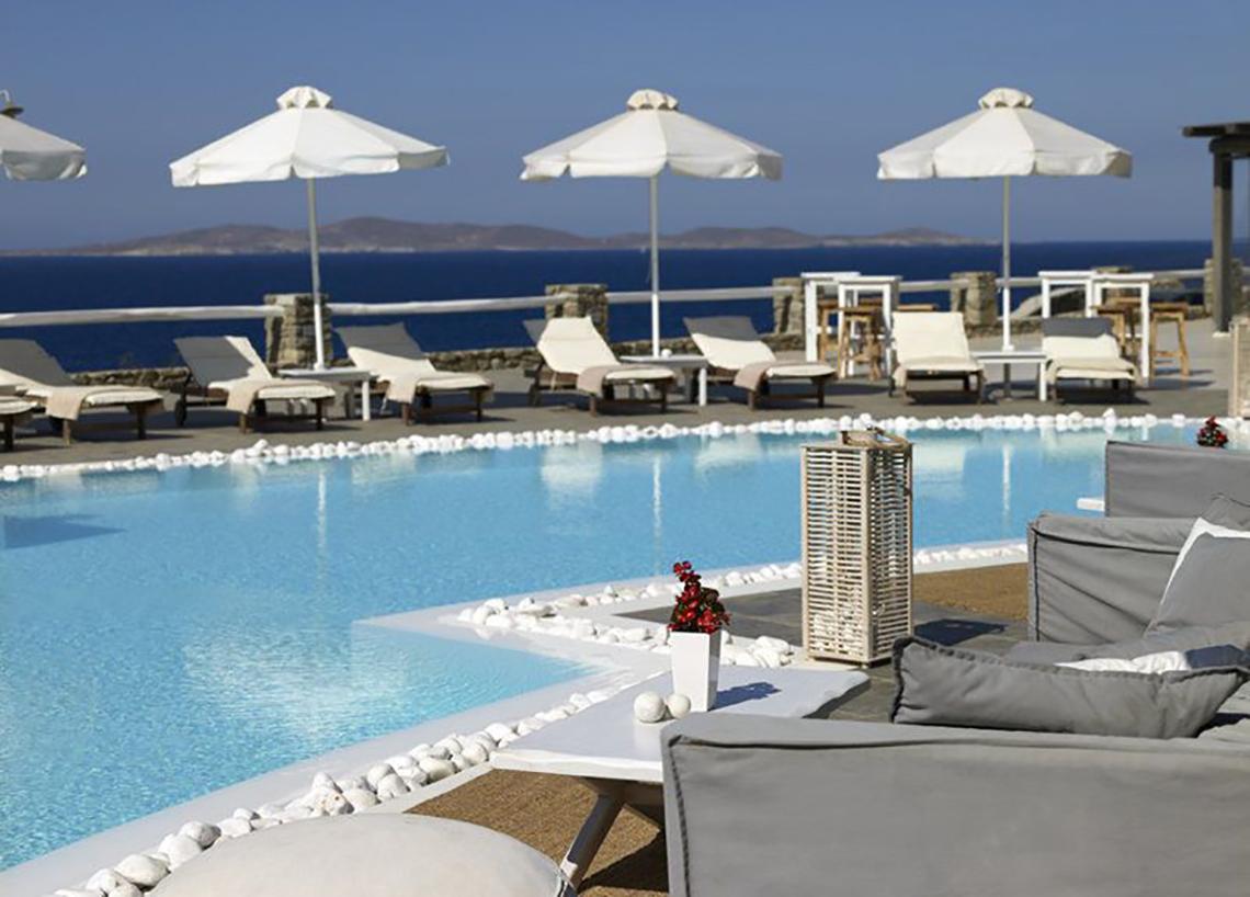 Pool des Rocabella Mykonos Art Hotel & Spa mit Liegestühlen und Schirmen.