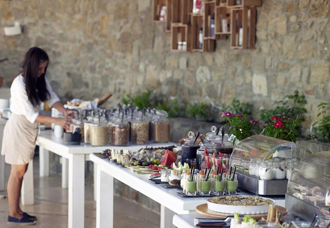 Frühstücksbuffet im Rocabella Mykonos Art Hotel & Spa mit einer Frau, die Essen serviert.