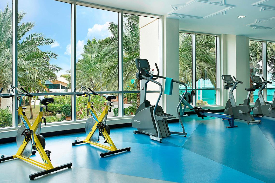 Fitnessstudio im Habtoor Grand Resort & Spa mit großen Fenstern und Trainingsgeräten.