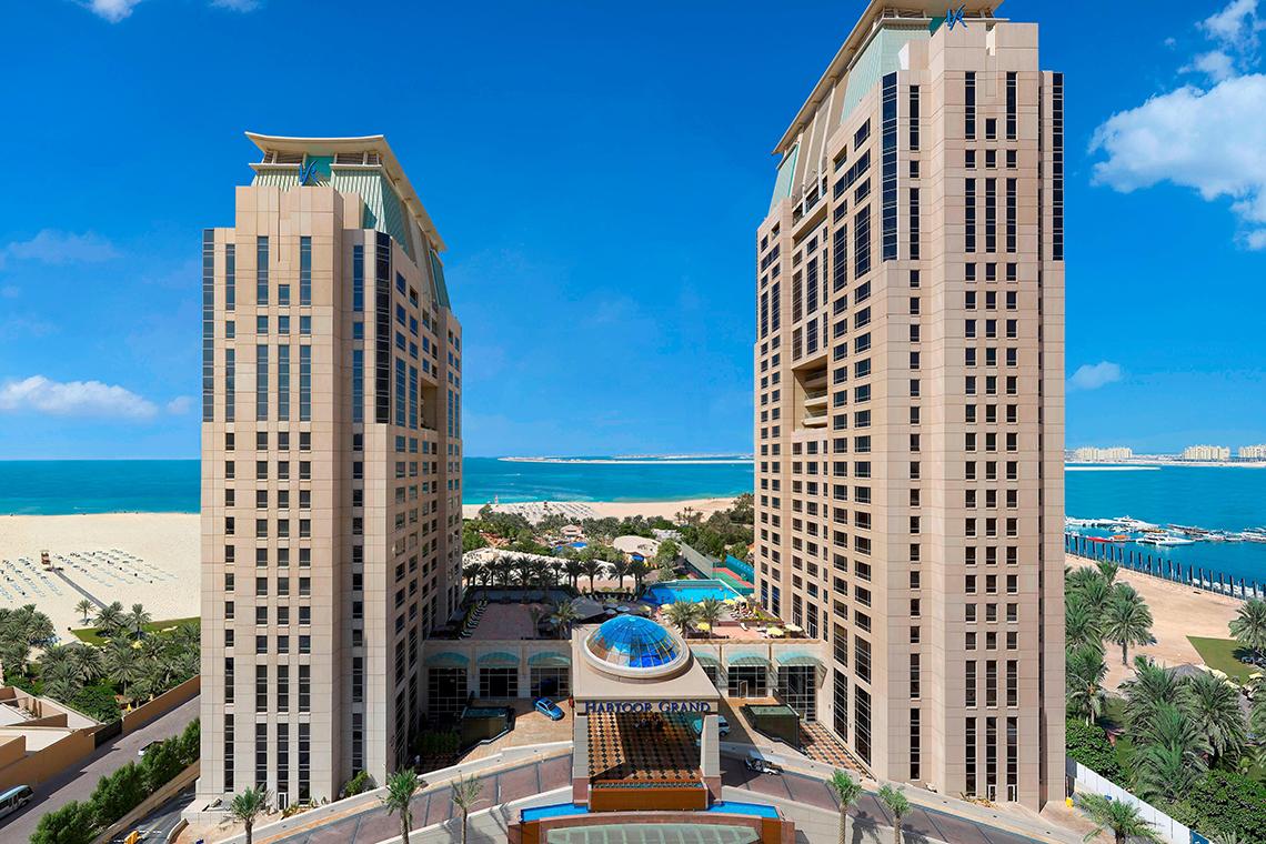 Luftaufnahme des Habtoor Grand Resort & Spa mit Blick auf das Meer und die Gebäude.