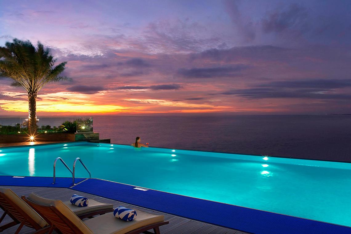 Habtoor Grand Resort & Spa Infinity Pool bei Sonnenuntergang mit Blick auf das Meer