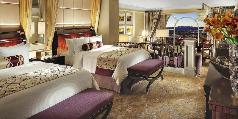 Innenansicht des Schlafzimmers im Venetian Resort Hotel & Casino mit zwei Betten, Nachttischen, einer Bank und einem Ausblick auf die Stadt.