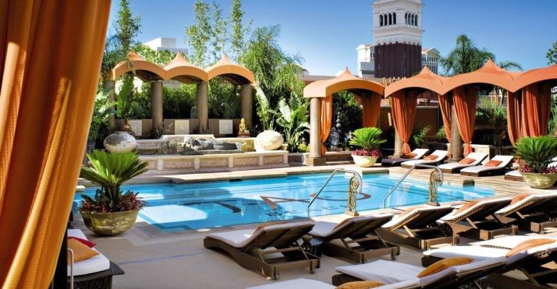 Außenpool des Venetian Resort Hotel & Casino mit Lounge-Stühlen und Pflanzen.