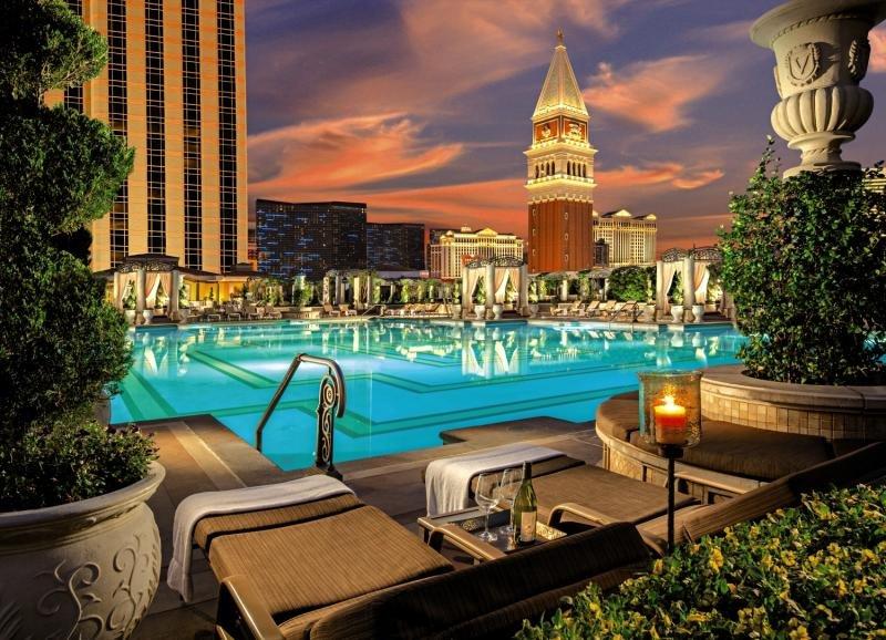 Außenpool des Venetian Resort Hotel & Casino bei Sonnenuntergang mit Lounge-Sesseln und Pflanzen