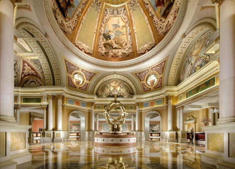 Innenansicht des Venetian Resort Hotel & Casino mit goldenen Deckengemälden und einer zentralen Skulptur.