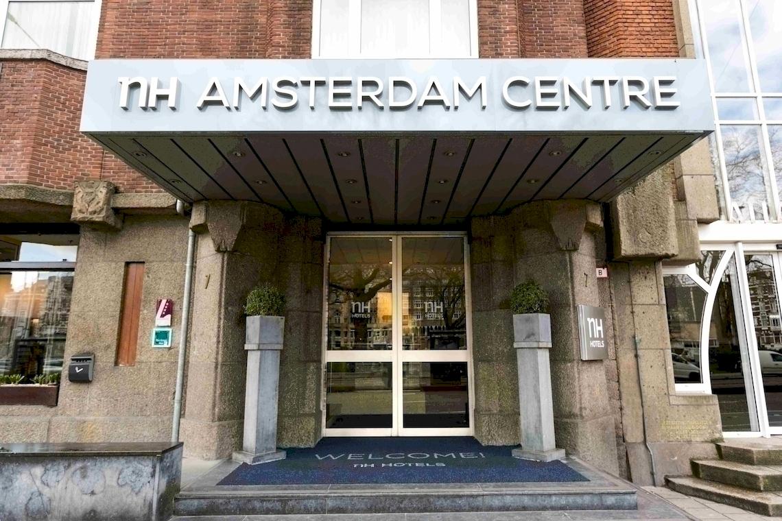 Eingang zum NH Amsterdam Centre Hotel mit Willkommensmatte und Glastür