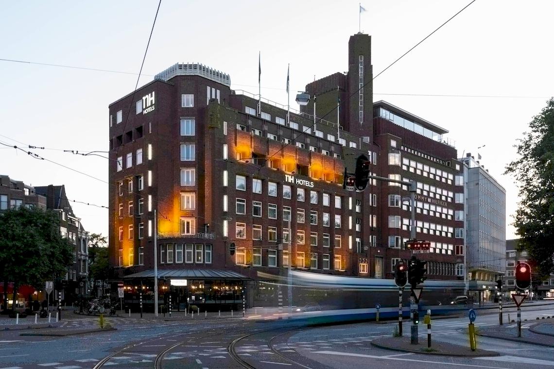 Das NH Amsterdam Centre Hotel Gebäude bei Abendlicht mit Beleuchtung.