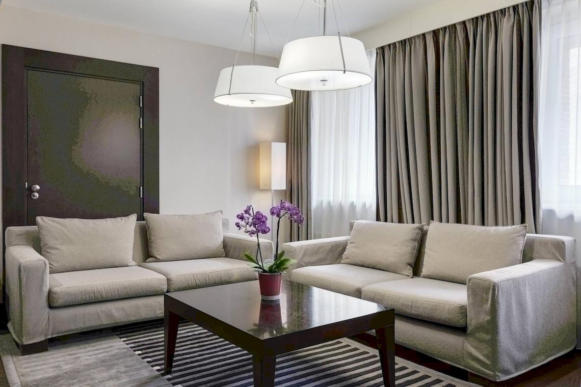 Wohnzimmer im NH Amsterdam Centre Hotel mit zwei Sofas, einem Tisch und dekorativen Elementen.