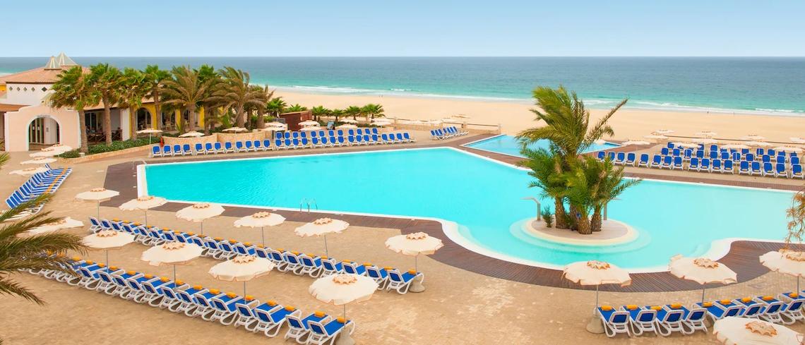 Außenpool des VOI Praia De Chaves Resorts mit vielen Liegestühlen und Sonnenschirmen am Strand