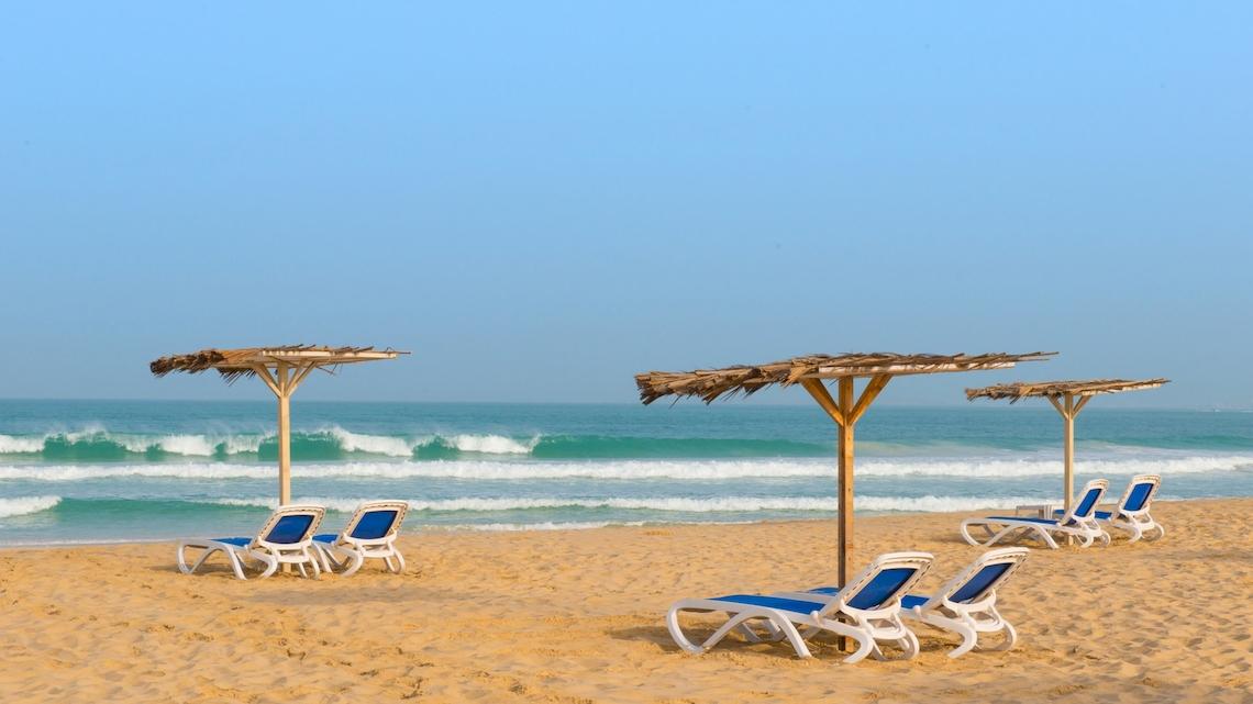 Sonnenliegen und Sonnenschirme am Strand des VOI Praia De Chaves Resort.