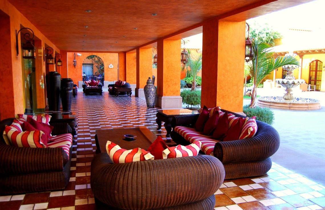 Lounge-Bereich des Hotel Villa Cortes mit orangefarbenen Wänden und gemusterten Bodenfliesen.