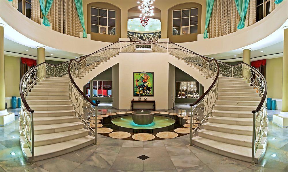Foyer des Iberostar Grand Rose Hall Hotels mit einer doppelgeschossigen Treppe und einem zentralen Brunnen.