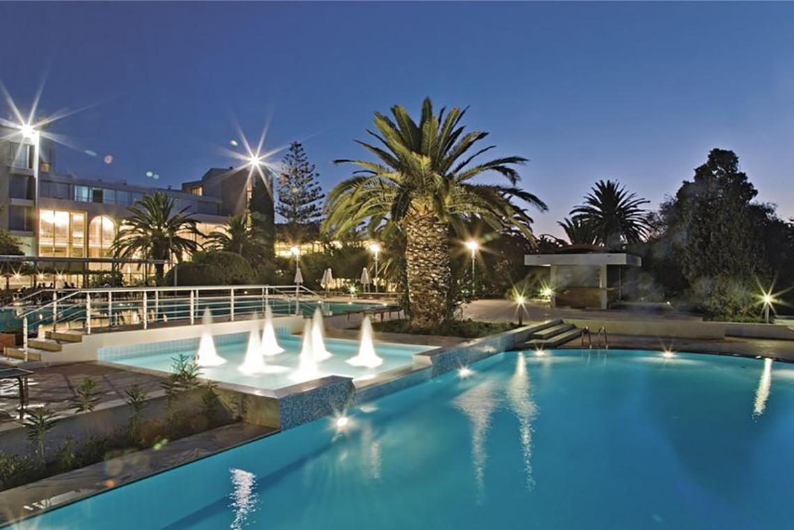 Der Pool des Caravia Beach Hotel bei Nacht mit Springbrunnen und Beleuchtung.