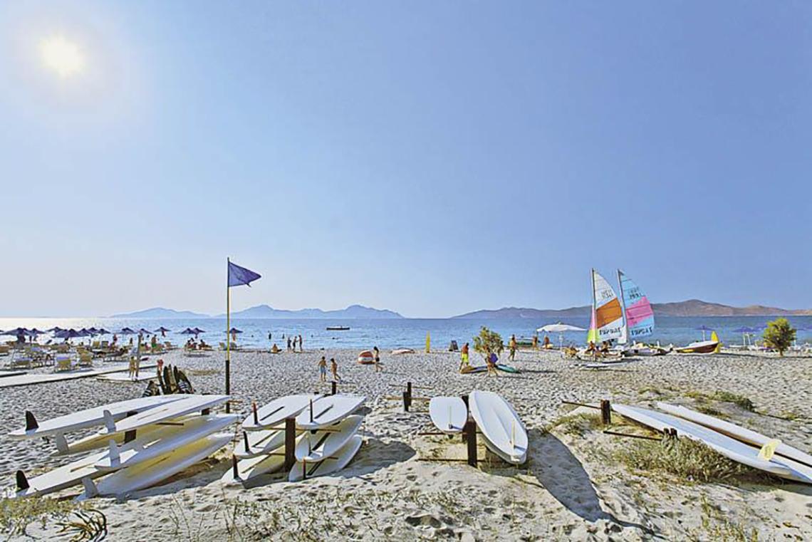 Sonnenuntergang am Strand mit mehreren Segelbooten und Surfbrettern am Caravia Beach Hotel & Bungalows