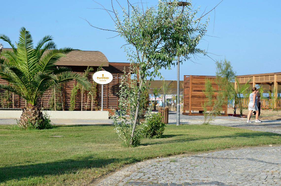 Außenbereich des Port Side Resorts mit Palme, Gehweg und hölzernen Strukturen.