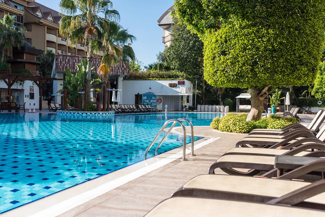 Außenpool des Port Side Resort Hotels mit Liegestühlen und Sonnenschirmen.