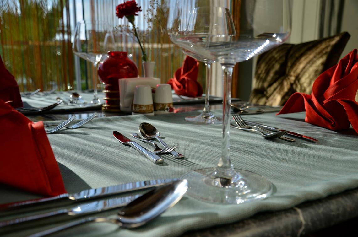 Tisch im Port Side Resort mit Geschirr und roten Servietten und Blumen.
