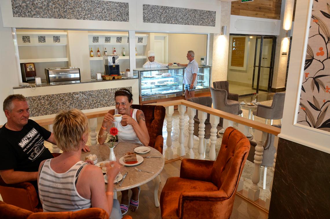 Vier Gäste im Restaurant des Port Side Resorts sitzen an einem Tisch und genießen ihr Essen.