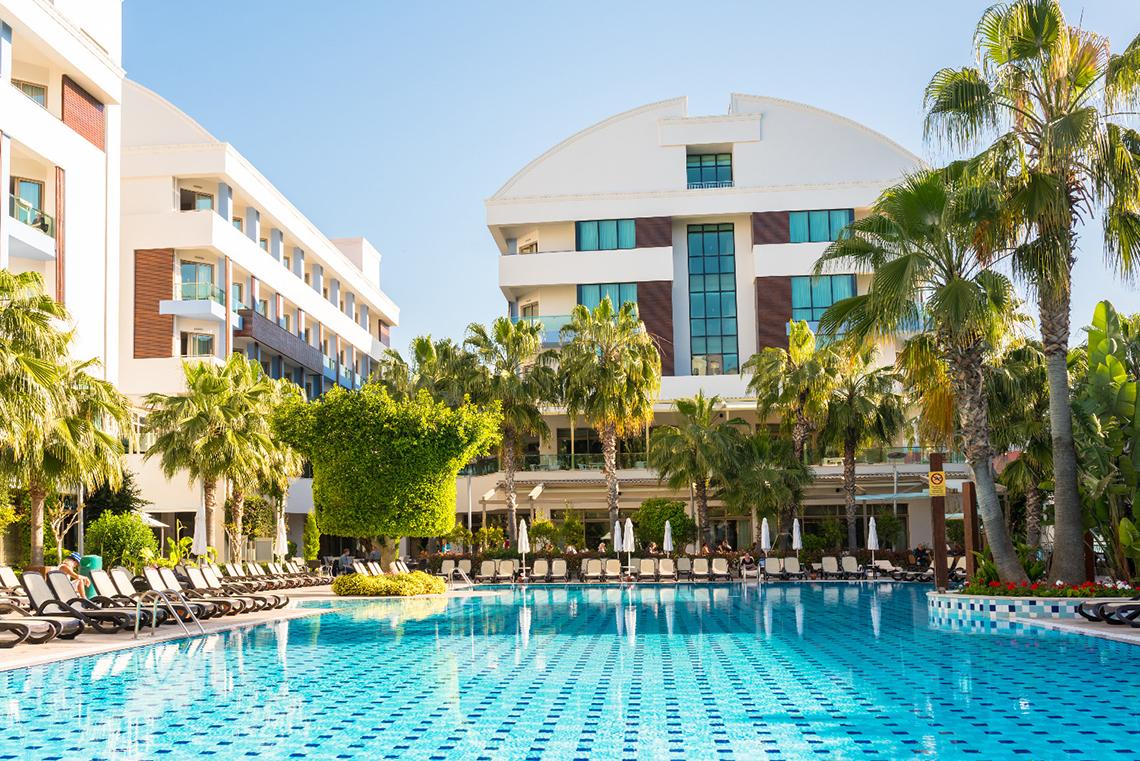 Außenbereich des Port Side Resort Hotels mit Swimmingpool und Palmen