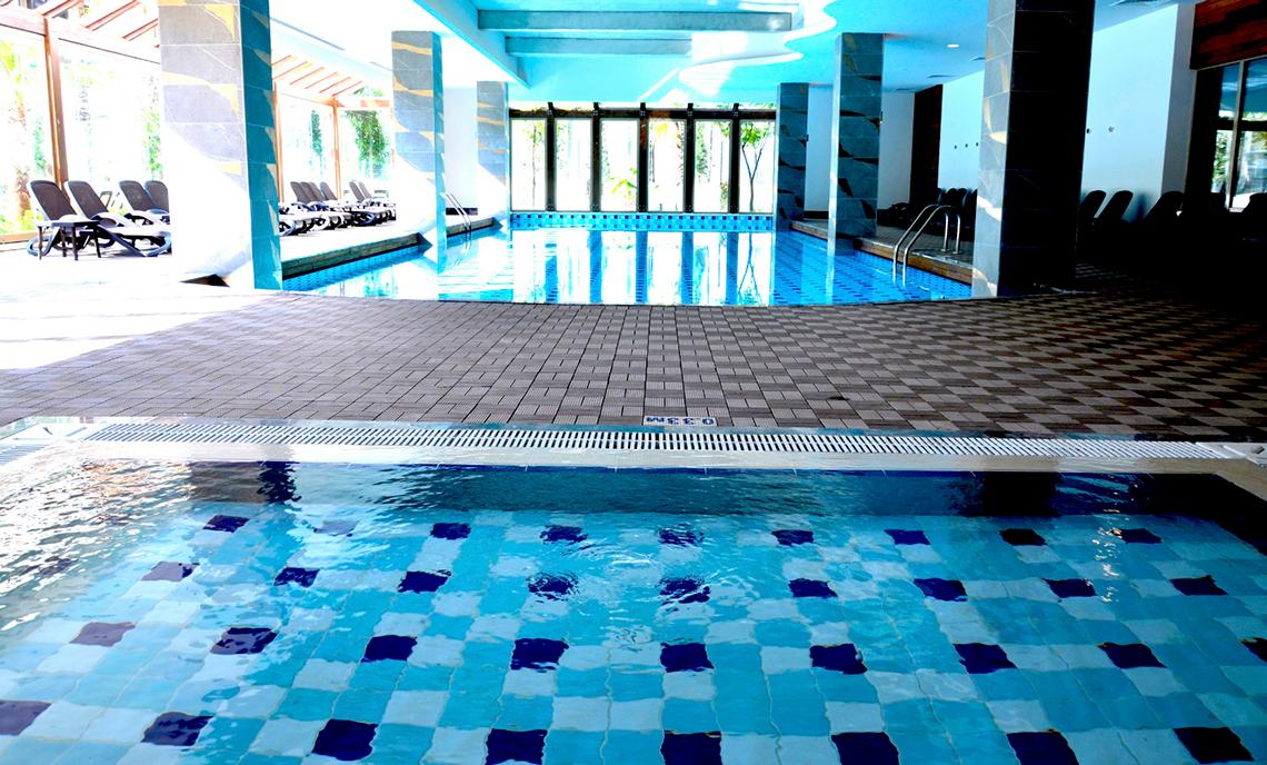 Innenpool des Port Side Resort mit blauen und weißen Fliesen und Loungebereich